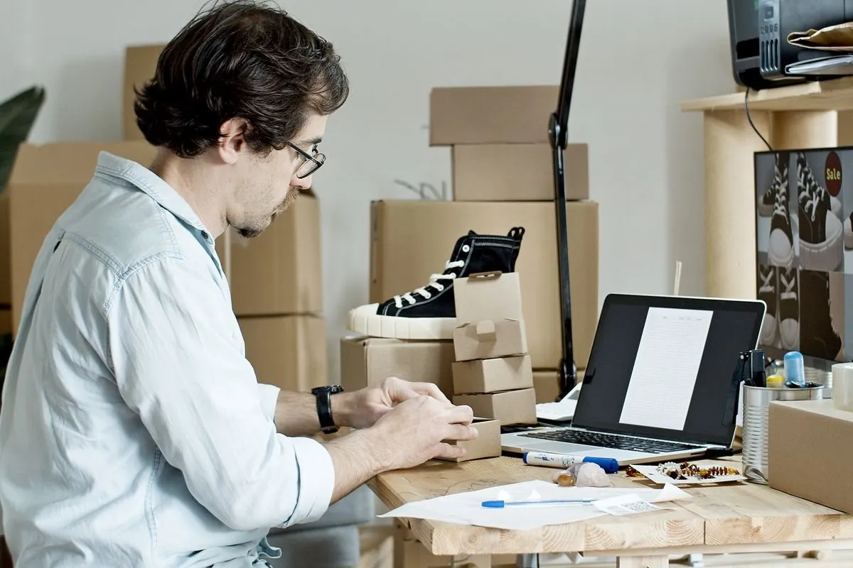 A small shop owner preparing an online order next to a laptop
